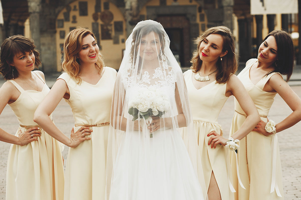 Pretty bridesmaids in yellow dresses stand behind bride hidden u